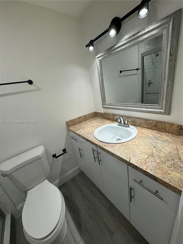a bathroom with a granite countertop toilet sink and mirror