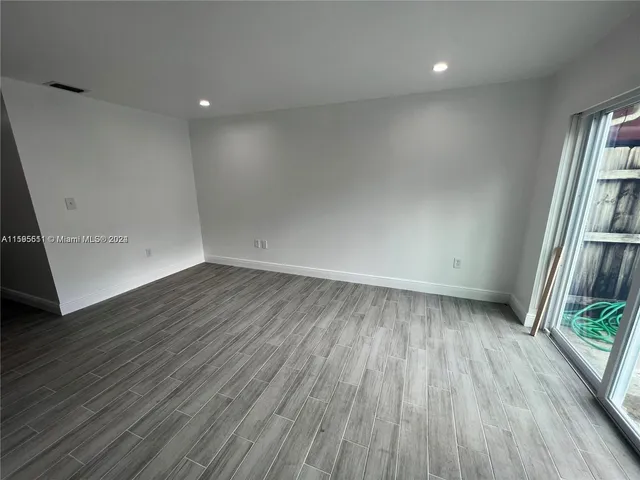 an empty room with wooden floor and entrance