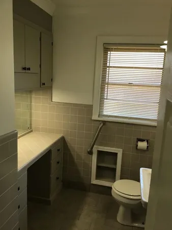 a bathroom with a toilet a sink a mirror and a window