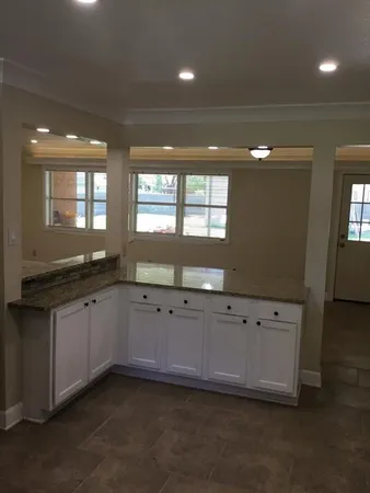 a kitchen with granite countertop white cabinets and sink