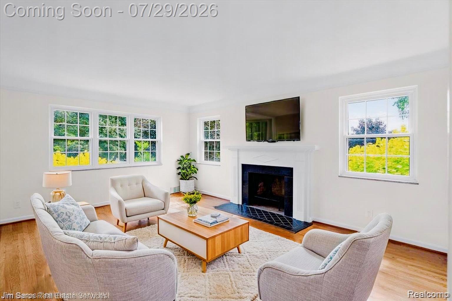 620 Neff Road Grosse Pointe, MI 48230 - Photo 3 of 14 Living room featuring a classic fireplace with a white mantel and black tile surround, hardwood flooring, and multiple windows