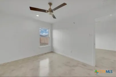 an empty room with windows and ceiling fan