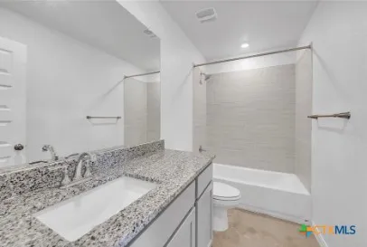 a bathroom with a granite countertop sink toilet and shower