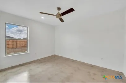 an empty room with a window and a ceiling fan
