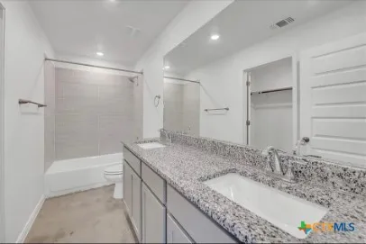 a bathroom with a granite countertop sink mirror and a bathtub