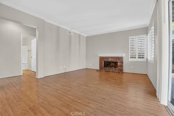 a view of empty room with wooden floor and windows