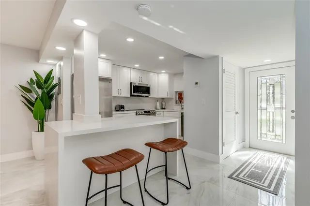 a kitchen with stainless steel appliances kitchen island granite countertop a refrigerator and a dining table