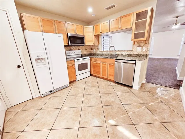 a kitchen with stainless steel appliances a refrigerator sink stove and white cabinets