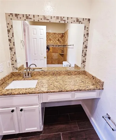 a bathroom with a granite countertop sink and a mirror