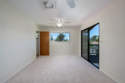 an empty room with windows and ceiling fan