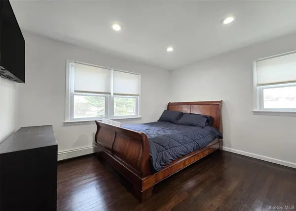 a bedroom with a bed and a flat tv screen on the dresser