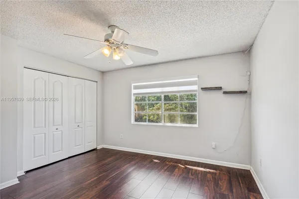 an empty room with wooden floor chandelier fan and windows