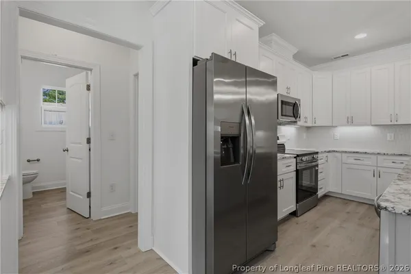 a kitchen with stainless steel appliances granite countertop white cabinets and a stove top oven