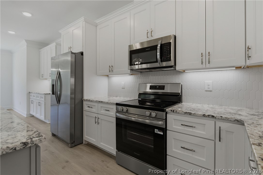 3223 Leaflet Church Road Broadway, NC 27505 - Photo 13 of 30 a kitchen with stainless steel appliances granite countertop white cabinets and a stove top oven