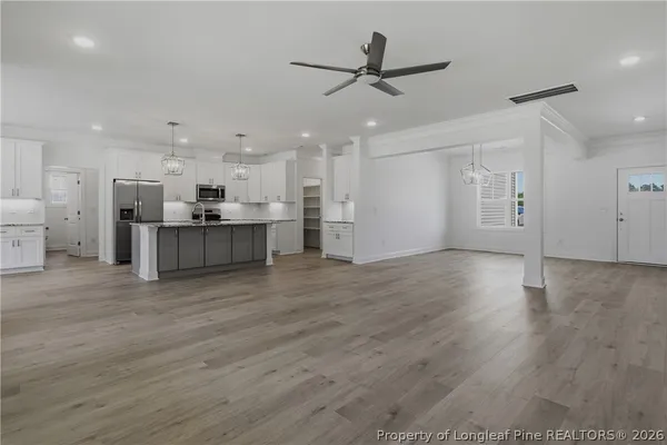 a view of a kitchen with a stove top oven a refrigerator with wooden floor
