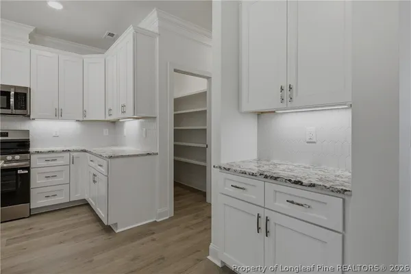 a kitchen with granite countertop white cabinets and appliances