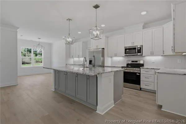 a kitchen with kitchen island granite countertop a sink cabinets and stainless steel appliances