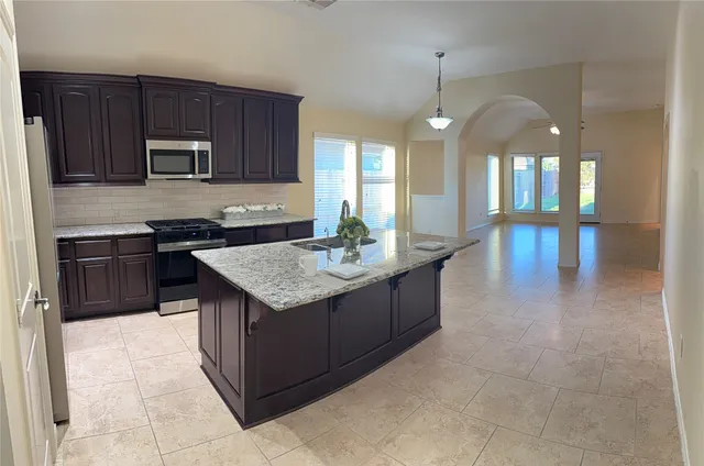 a kitchen with kitchen island granite countertop a stove oven and a sink with granite countertops