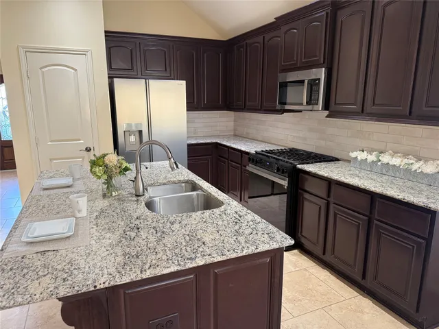 a kitchen with granite countertop a sink a stove and cabinets