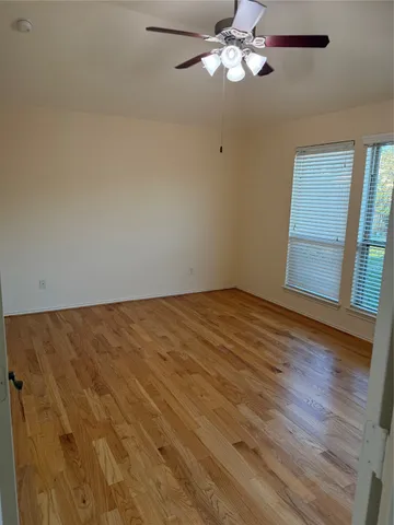 an empty room with wooden floor fan and window
