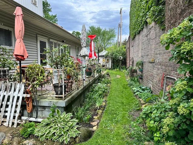 a view of house with a yard and potted plants