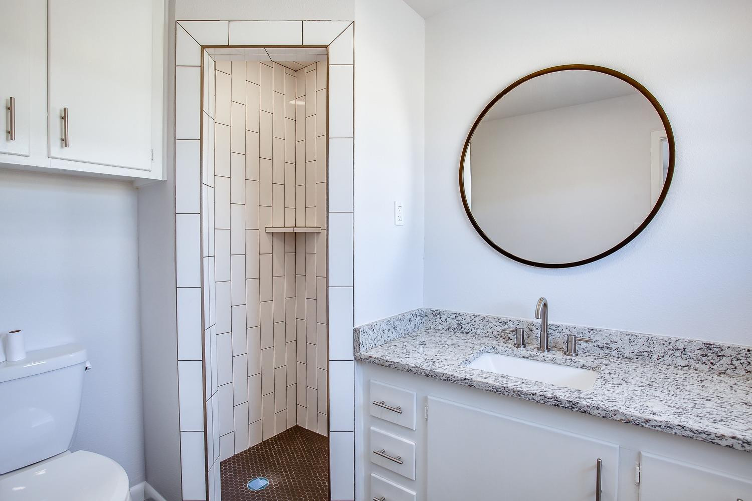 3410 53rd Street Lubbock, TX 79413 - Photo 11 of 14 a bathroom with a granite countertop toilet sink and mirror