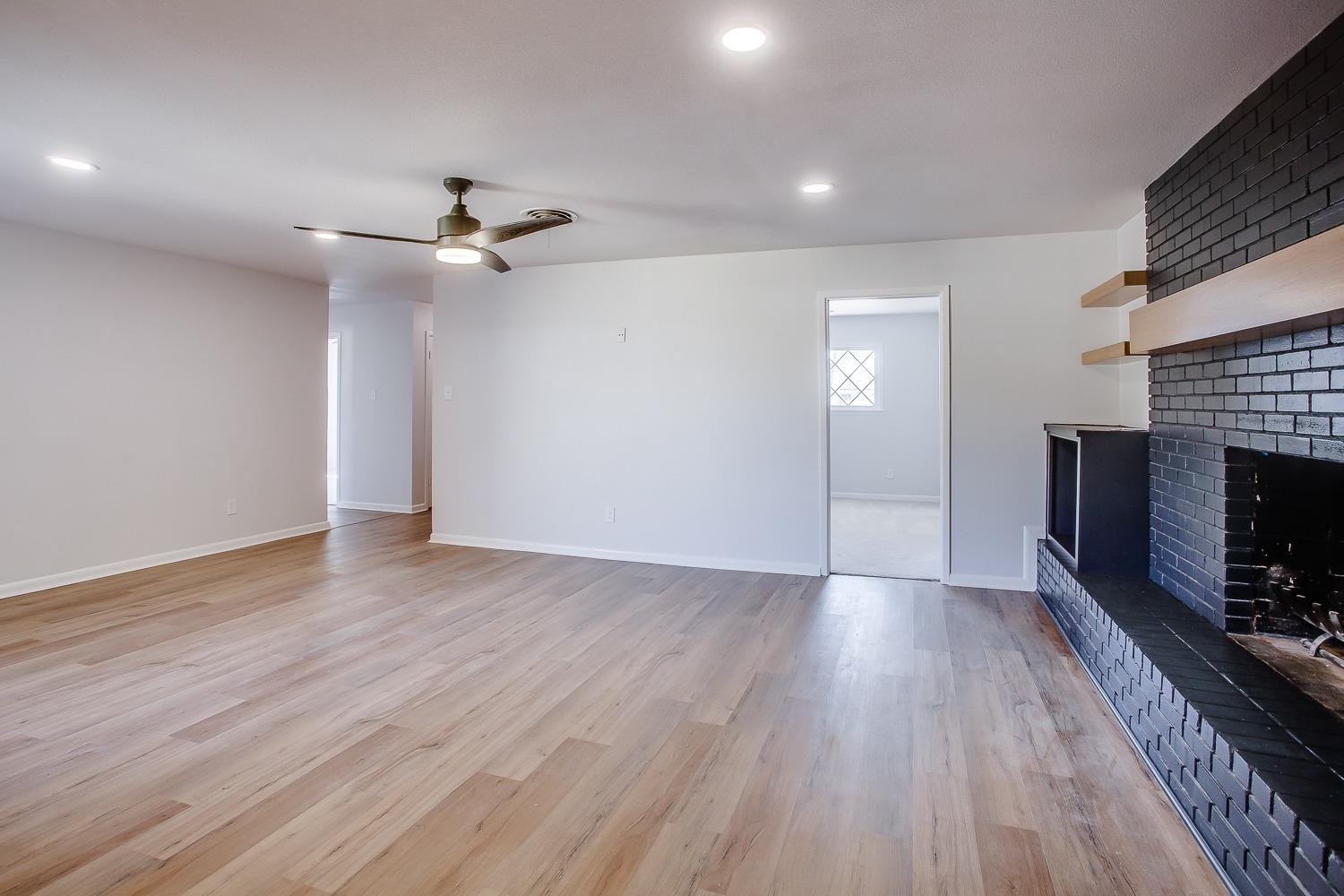3410 53rd Street Lubbock, TX 79413 - Photo 5 of 14 an empty room with wooden floor fireplace and fan