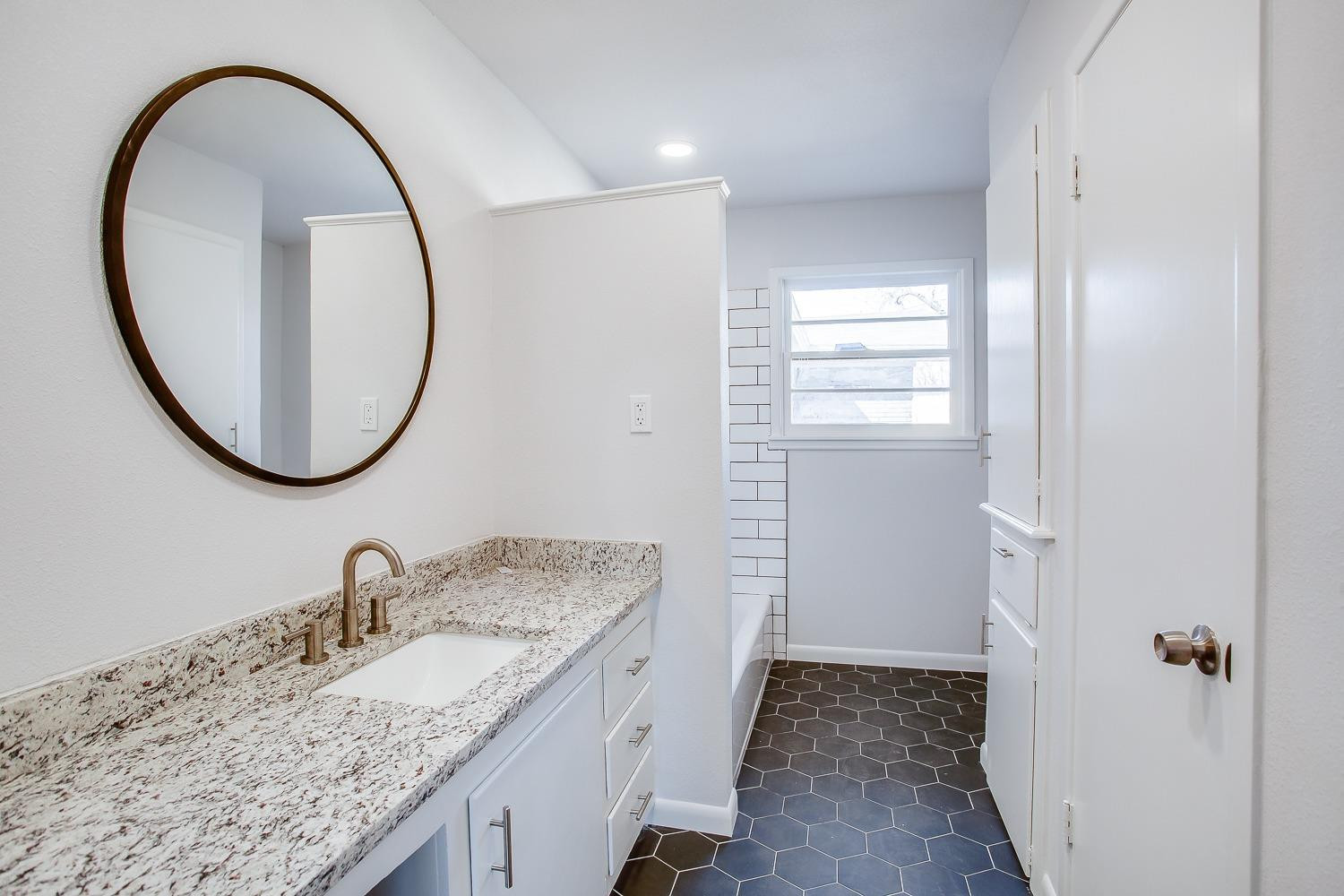 3410 53rd Street Lubbock, TX 79413 - Photo 10 of 14 a bathroom with a granite countertop sink a mirror and a shower