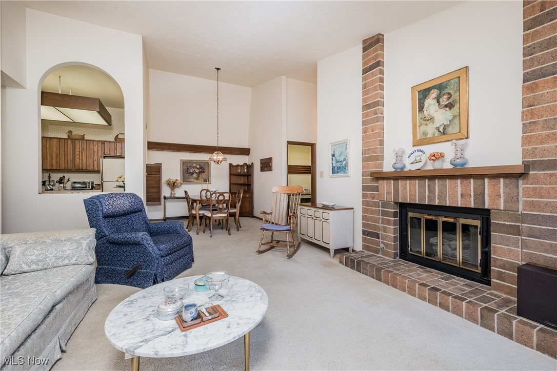 Living area with a high ceiling, carpet flooring, a fireplace, and a toaster