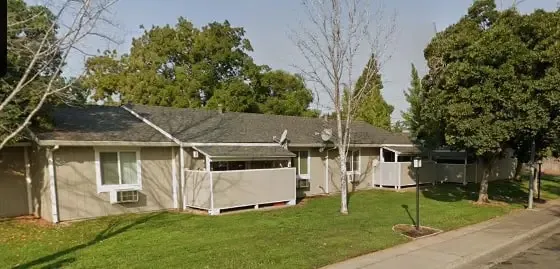 a view of a white house with a big yard and large trees