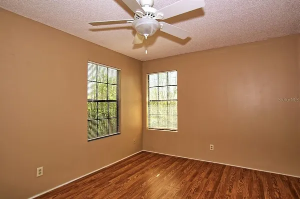 an empty room with windows and fan