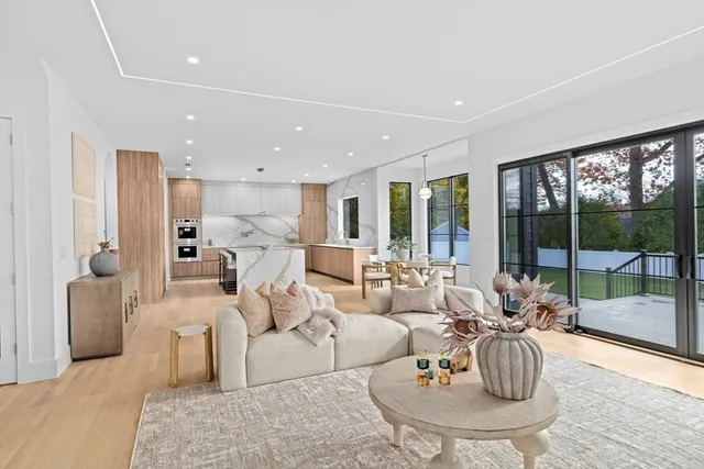 a living room with furniture large windows and wooden floor