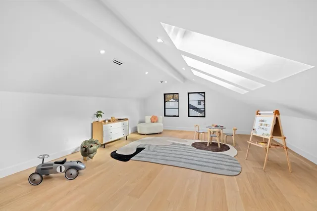 a living room with couches and kitchen view with wooden floor