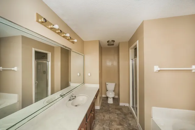 a spacious bathroom with a granite countertop sink a mirror and a shower
