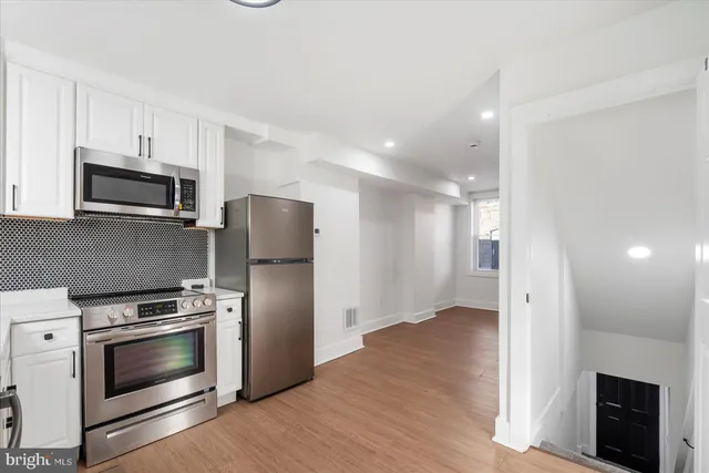 a kitchen with a refrigerator stove and wooden floor
