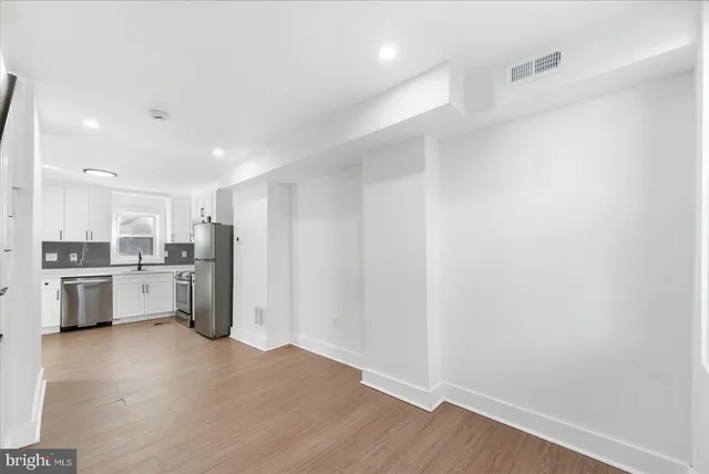 a view of a kitchen with a sink and dishwasher a refrigerator with wooden floor