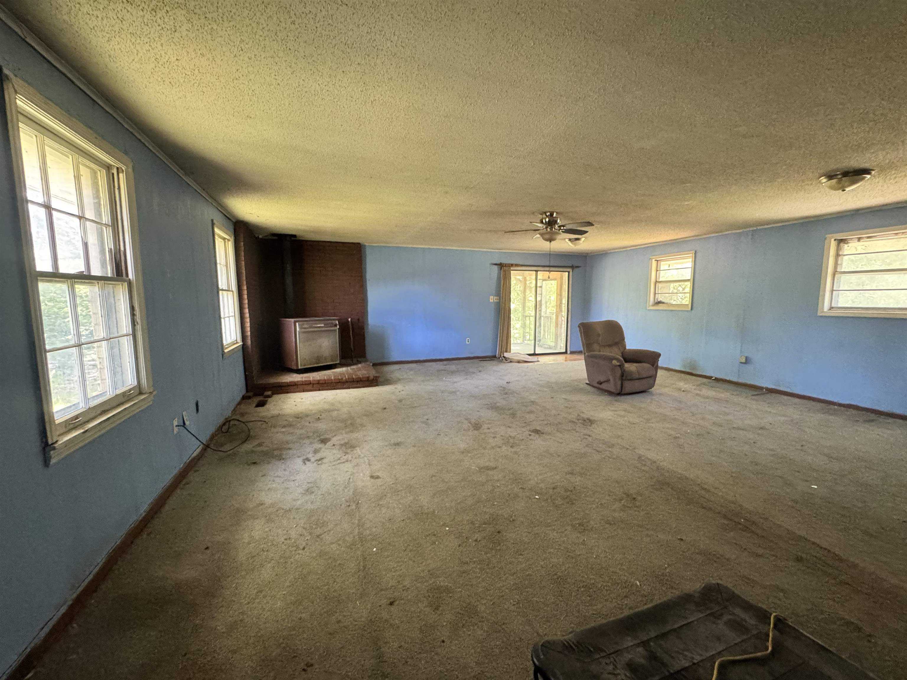 4712 Drummonds Road Drummonds, TN 38023 - Photo 29 of 38 Spacious interior room featuring multiple windows, a ceiling fan, a brick fireplace surround with an insert, and a sliding glass door
