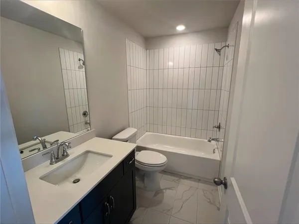 a bathroom with a bathtub shower sink mirror vanity and toilet