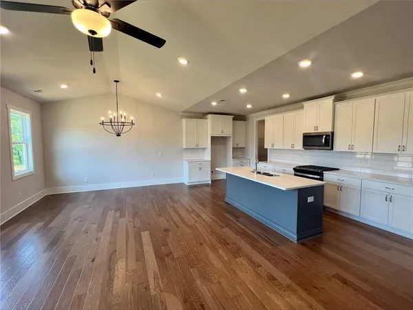 a kitchen with stainless steel appliances granite countertop a sink a stove a refrigerator cabinets and wooden floor