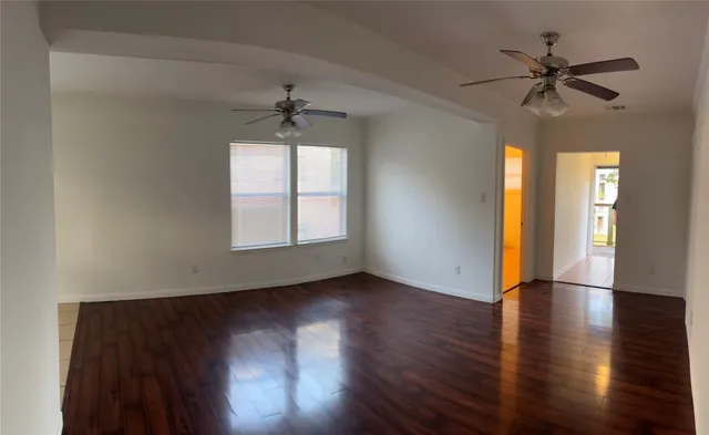 a view of empty room with wooden floor and fan