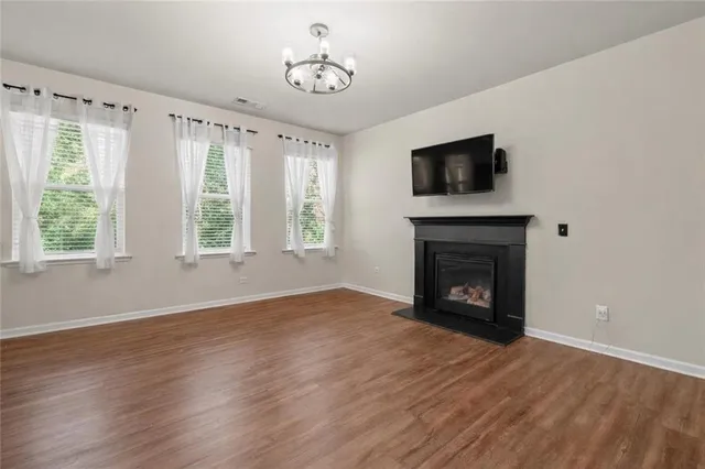an empty room with windows fireplace and wooden floor