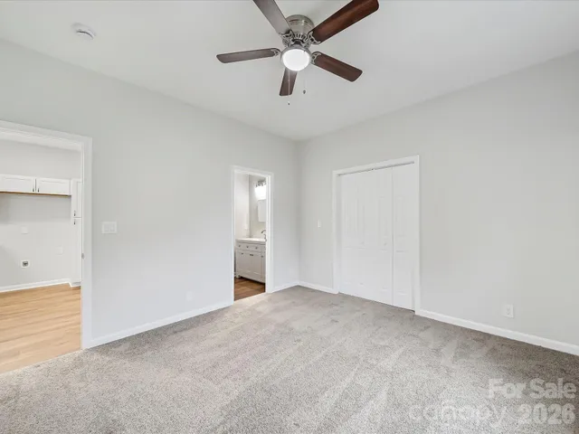 an empty room with closet and a ceiling fan