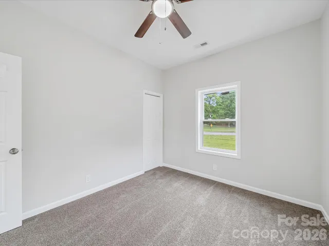an empty room with a window and a fan
