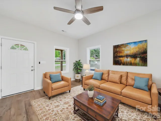 a living room with furniture kitchen view and a chandelier