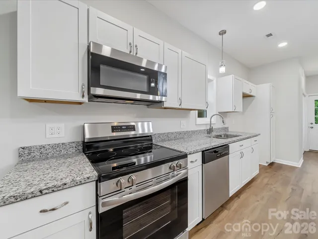 a kitchen with stainless steel appliances granite countertop a sink stove and microwave