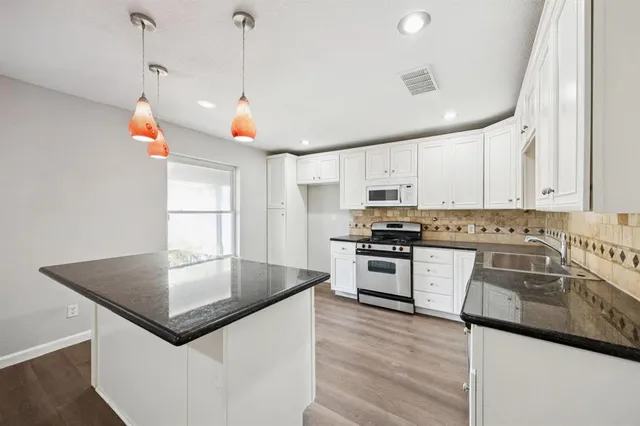 a kitchen with granite countertop a sink a counter space appliances and cabinets