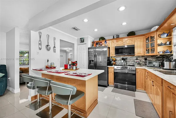 a kitchen with stainless steel appliances kitchen island granite countertop a stove refrigerator and a sink
