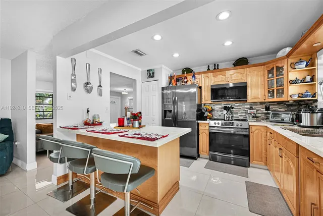 a kitchen with stainless steel appliances kitchen island granite countertop a stove refrigerator and a sink