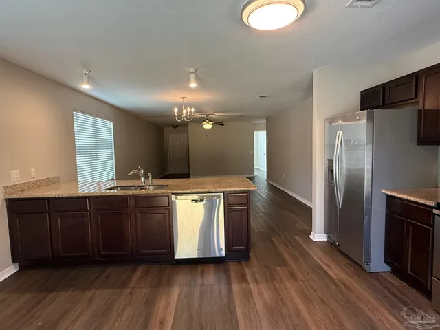 a large kitchen with a center island wooden floor stainless steel appliances and cabinets