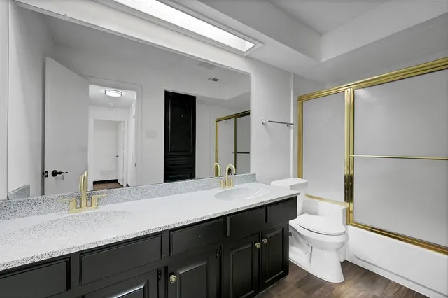a bathroom with a double vanity sink toilet mirror and bathtub